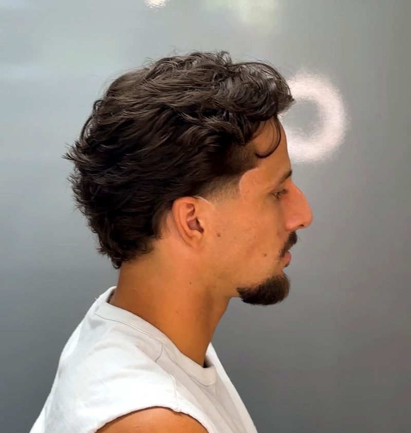 Gewelltes Deckhaar mit Fade an der Schläfe und Kinnbart, Seitenansicht